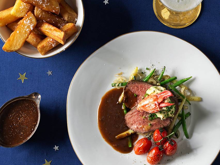 Biff med hummer, pommes frites och sås.