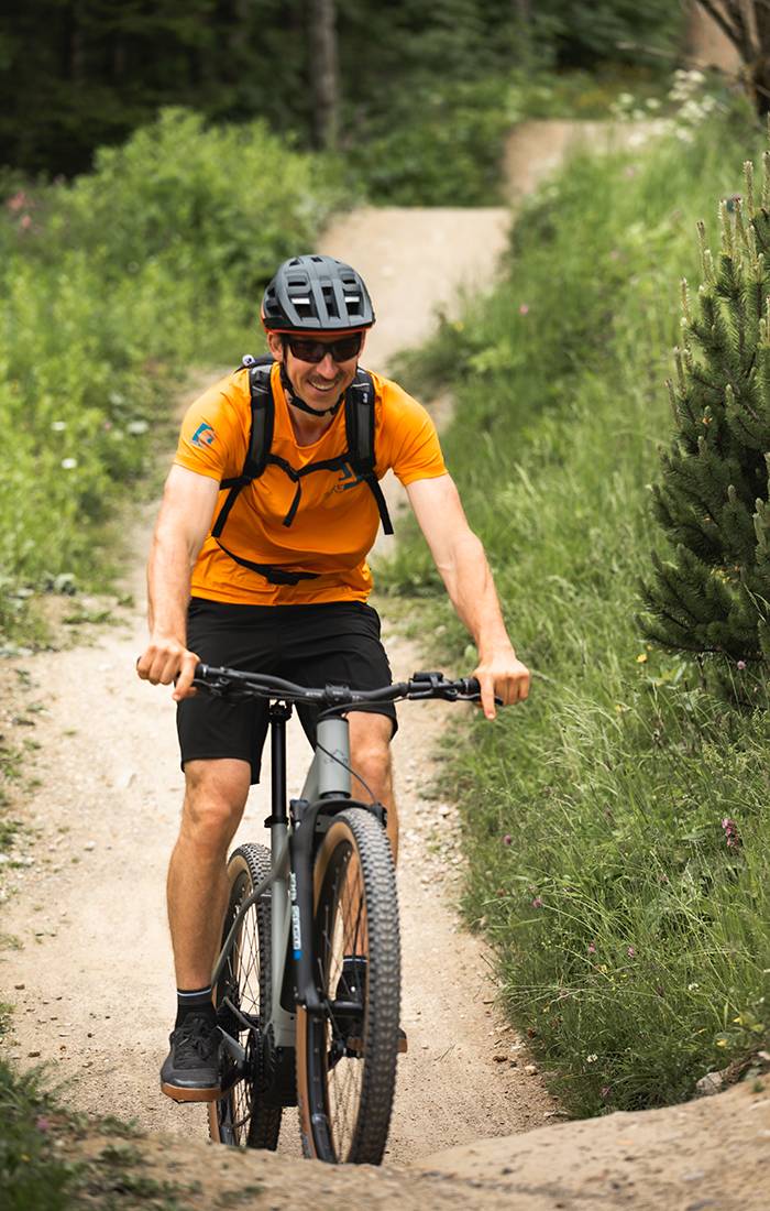 En glad man cyklar på en mountainbike i en skog.