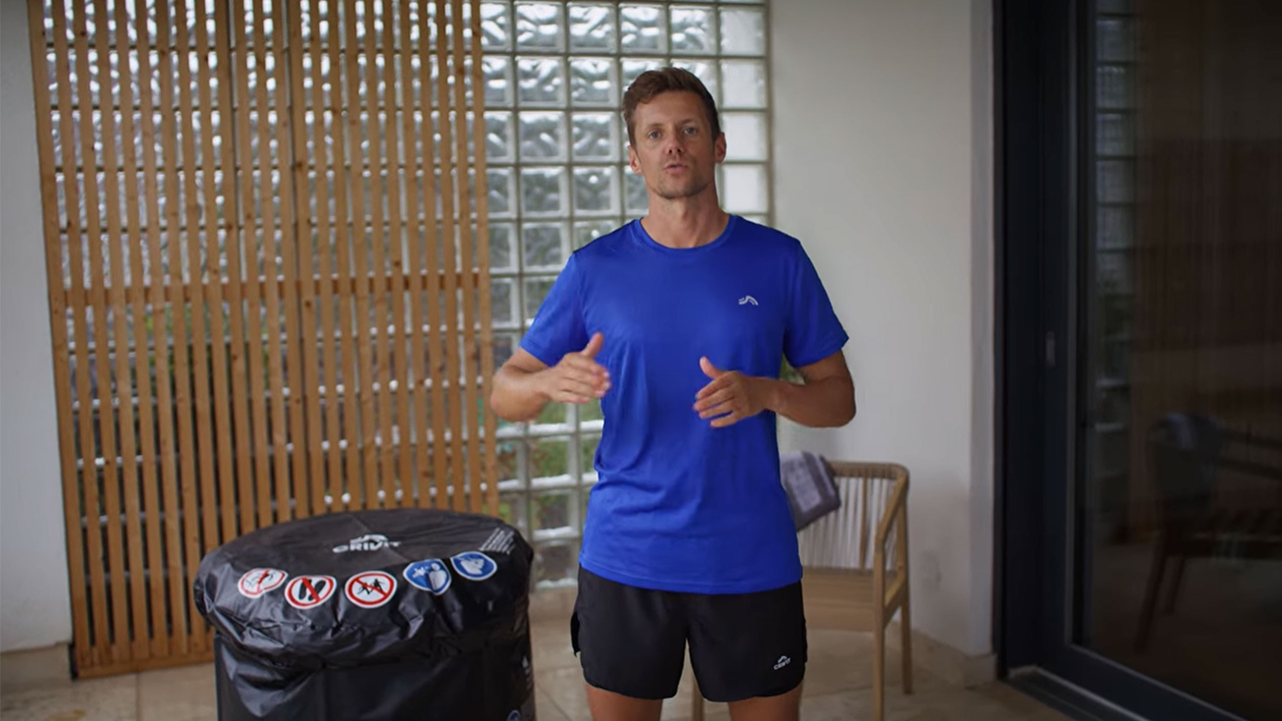 Man i blå T-shirt och svarta shorts, bredvid ett svart spabadsskydd.