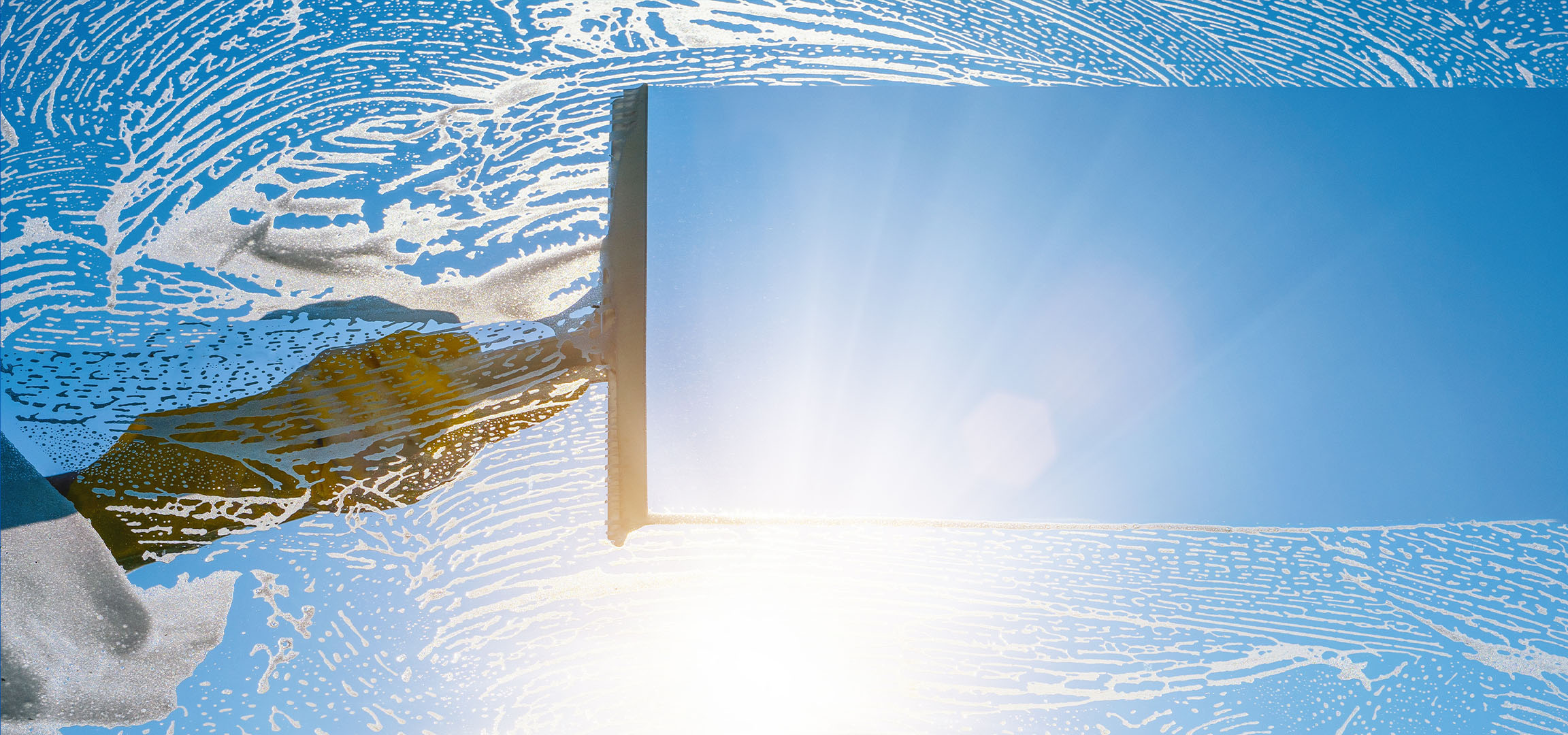 Fönsterputsning med tvålskum på en blå himmel.