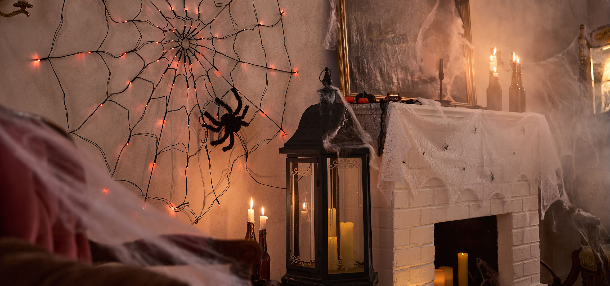 Halloween-dekorationer med spindelnätsbelysning, en stor spindel och ljus.