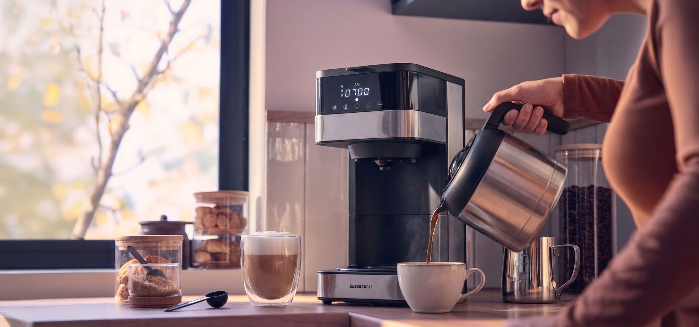 aiLabeling.aiLabelForImageAltText: Kaffemaskin häller kaffe i en kopp, med ett ljust fönster i bakgrunden.