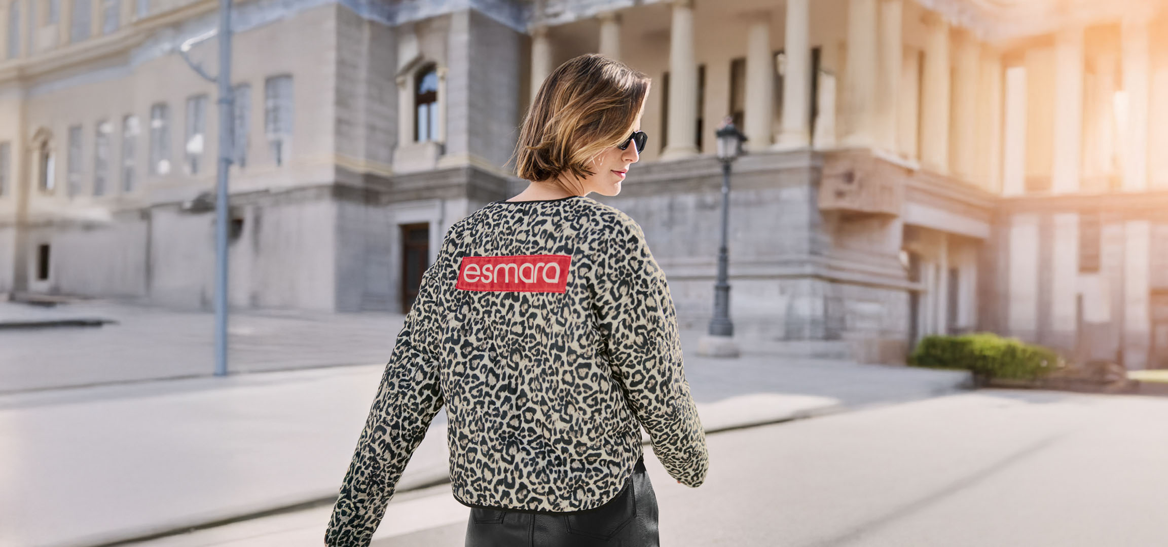 Kvinna i Esmara leopardjacka, solglasögon, på en stadsgata.