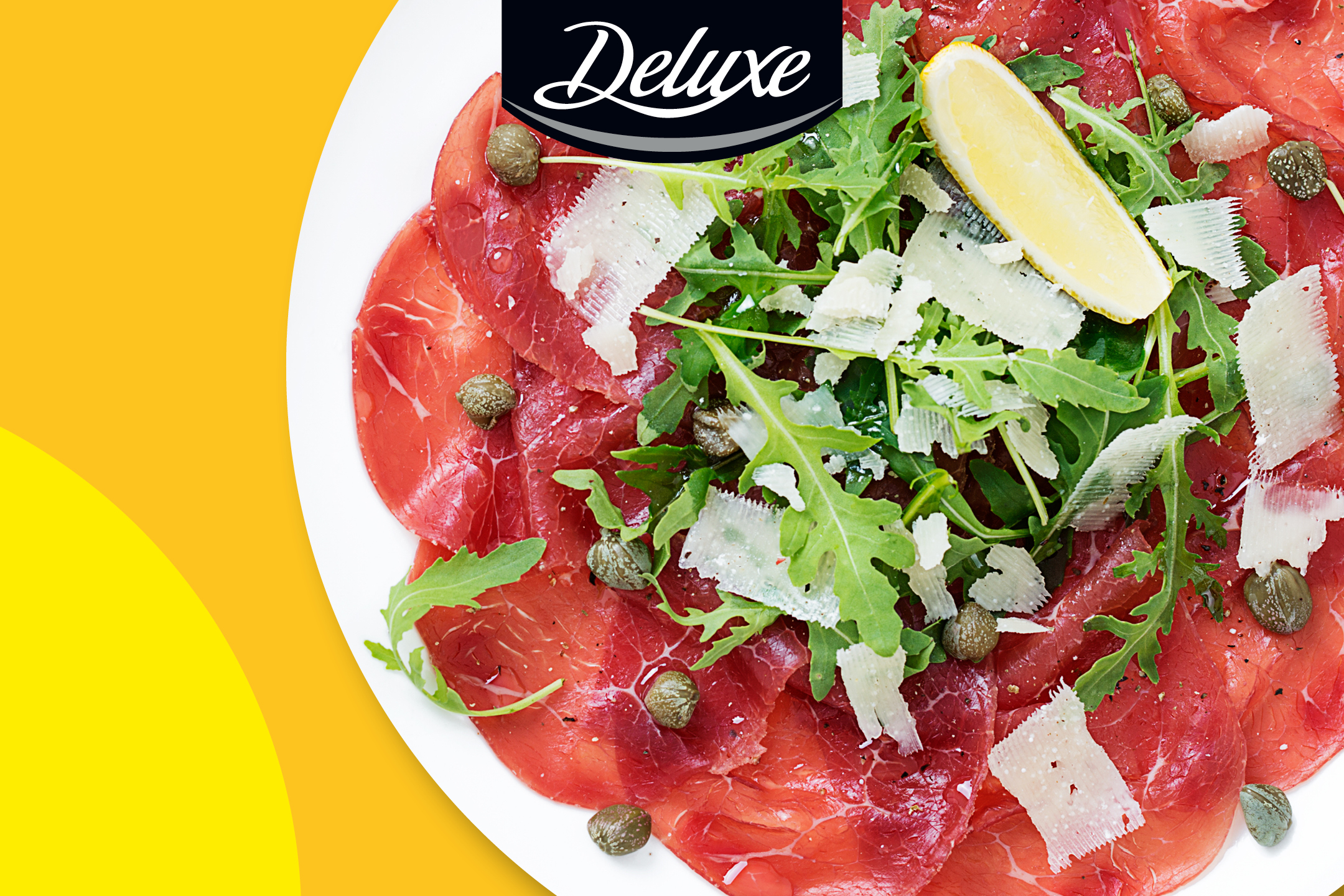 Carpaccio med ruccola, parmesan, kapris och citron på en vit tallrik.