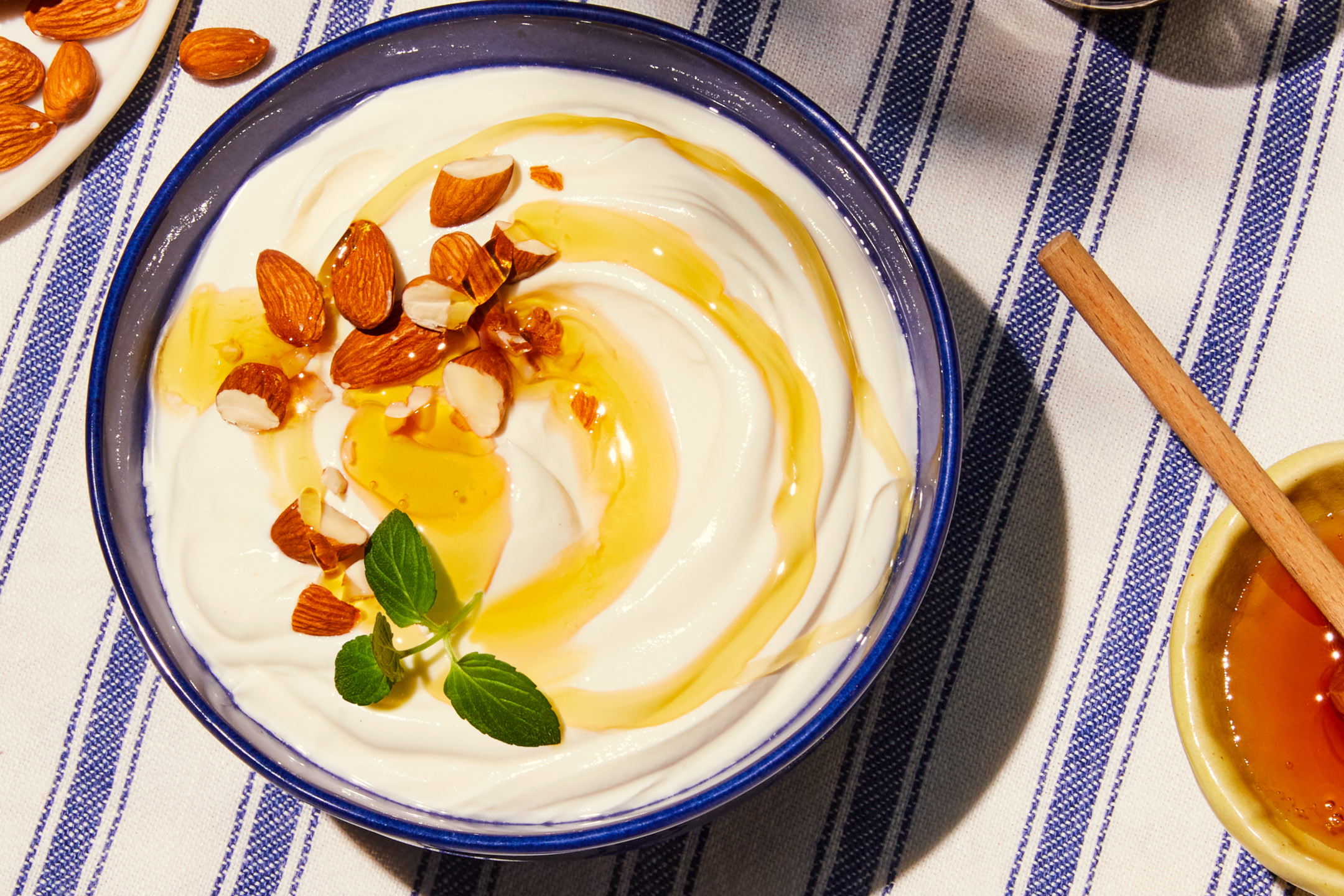 Yoghurt med mandel, honung och mynta på en randig duk.