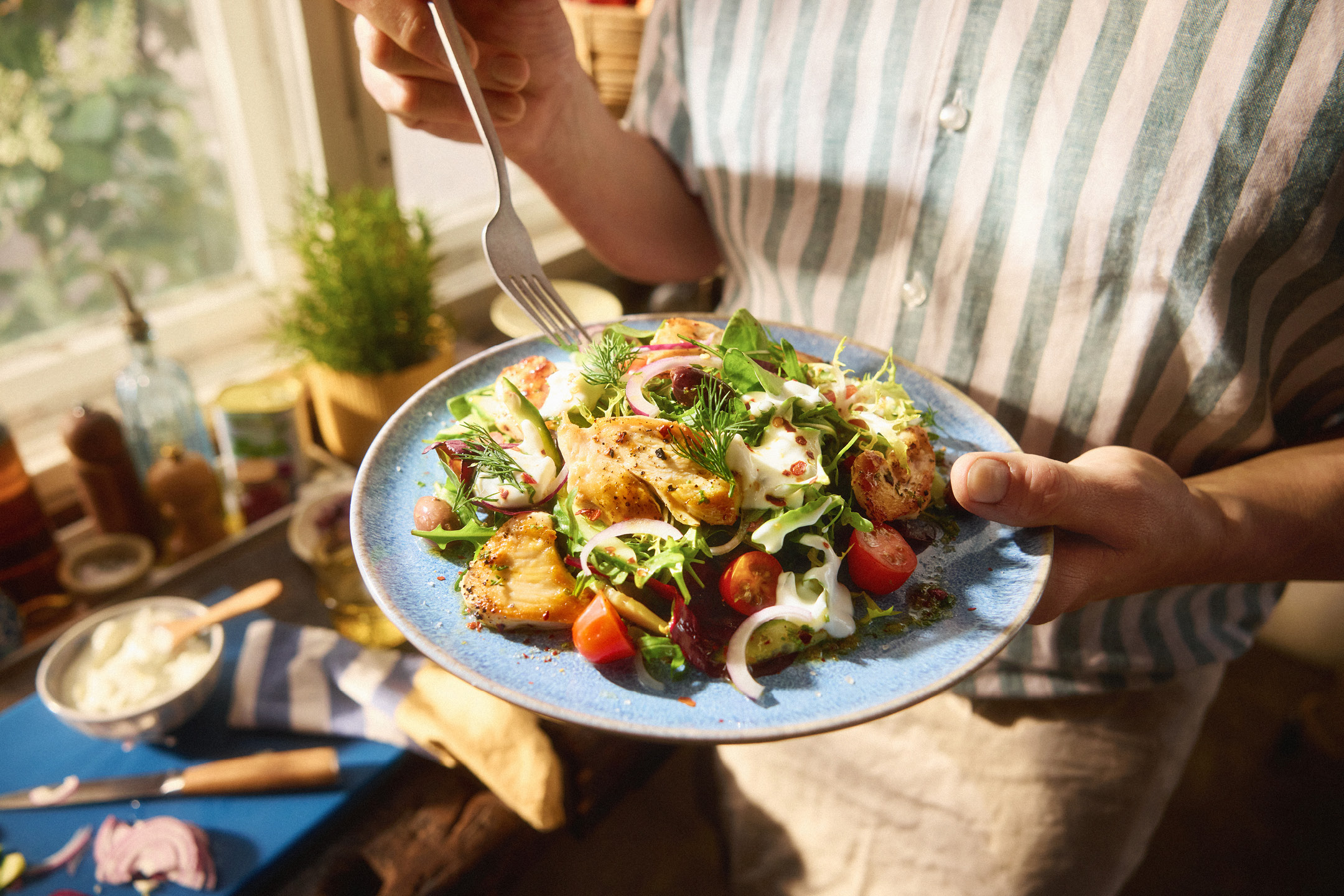En fräsch kycklingsallad med tomater, lök och krämig dressing serverad på en blå tallrik.