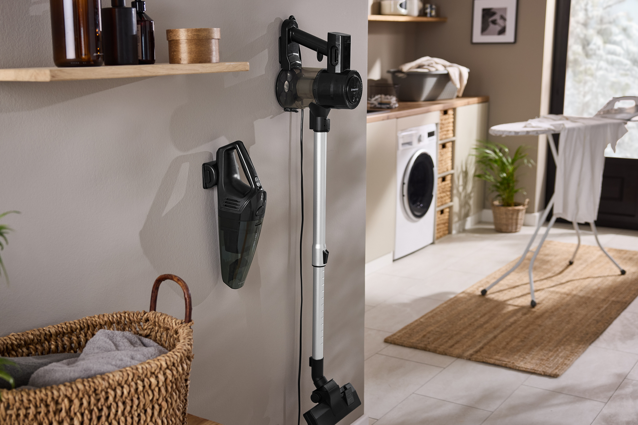 En sladdlös dammsugare och en handdammsugare monterade på väggen i en tvättstuga.