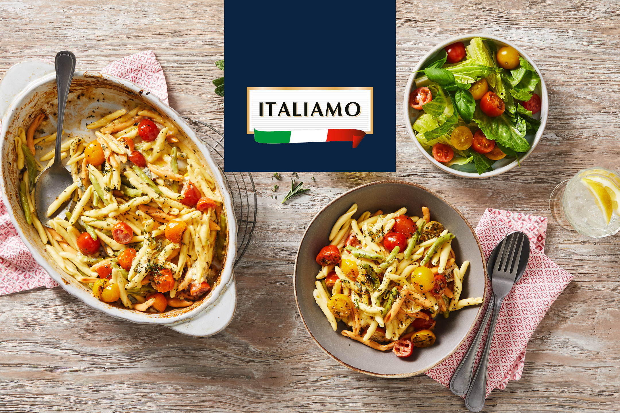 Italiamo-pasta med tomater och sallad på ett träbord.