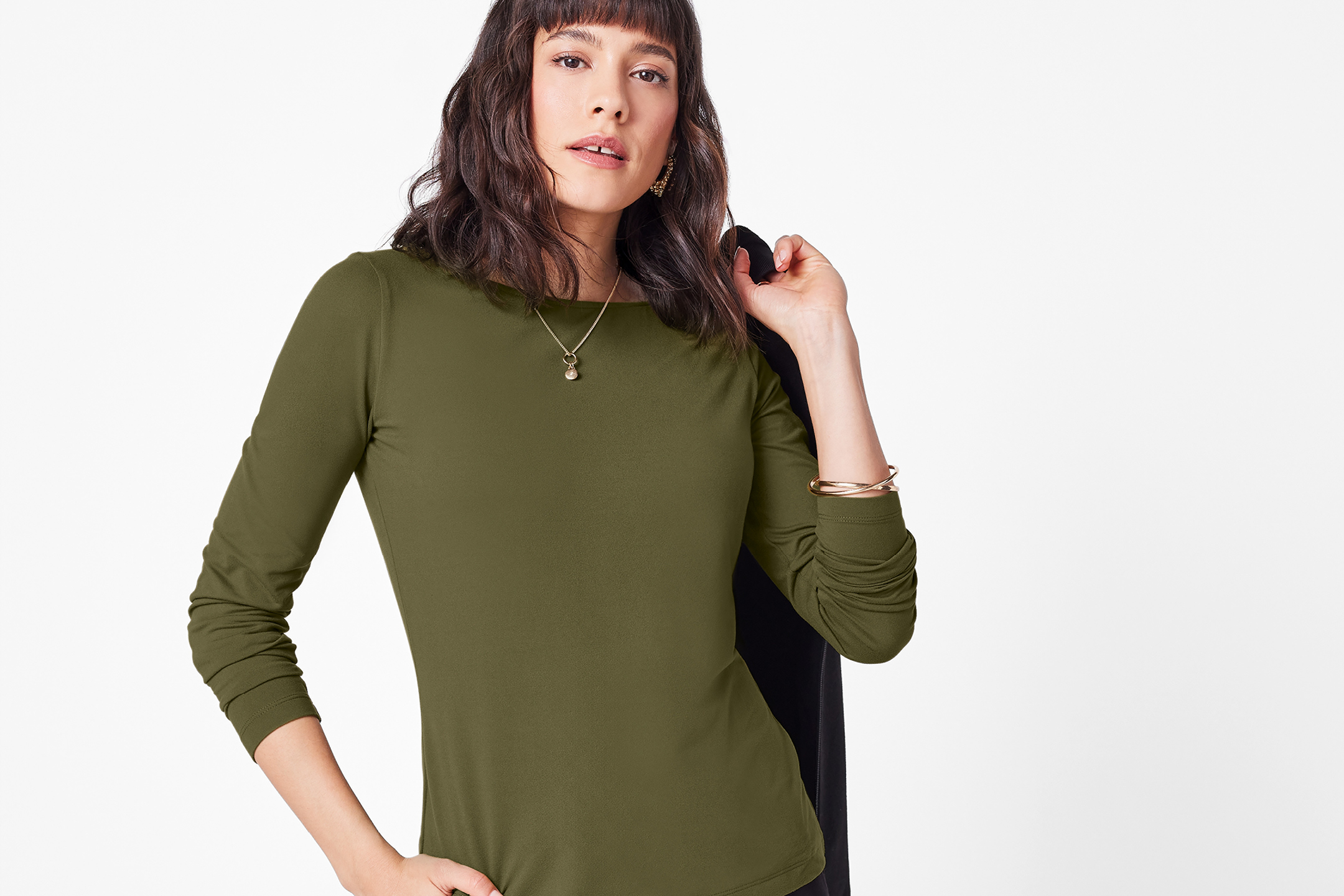 Kvinna i en olivgrön långärmad topp med en svart jacka över axeln.