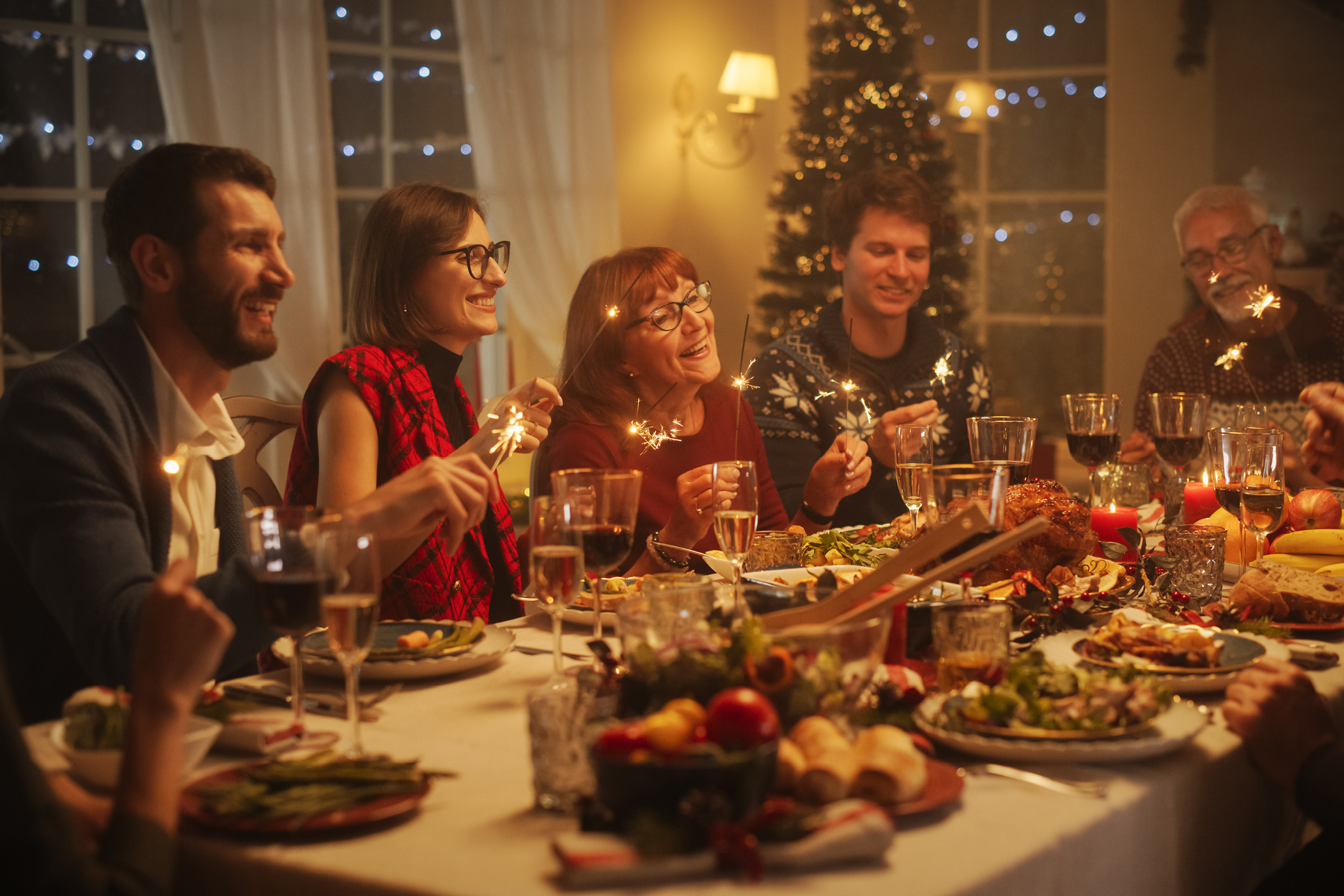 Familj och vänner firar julmiddag med gnistrande tomtebloss och festlig mat.