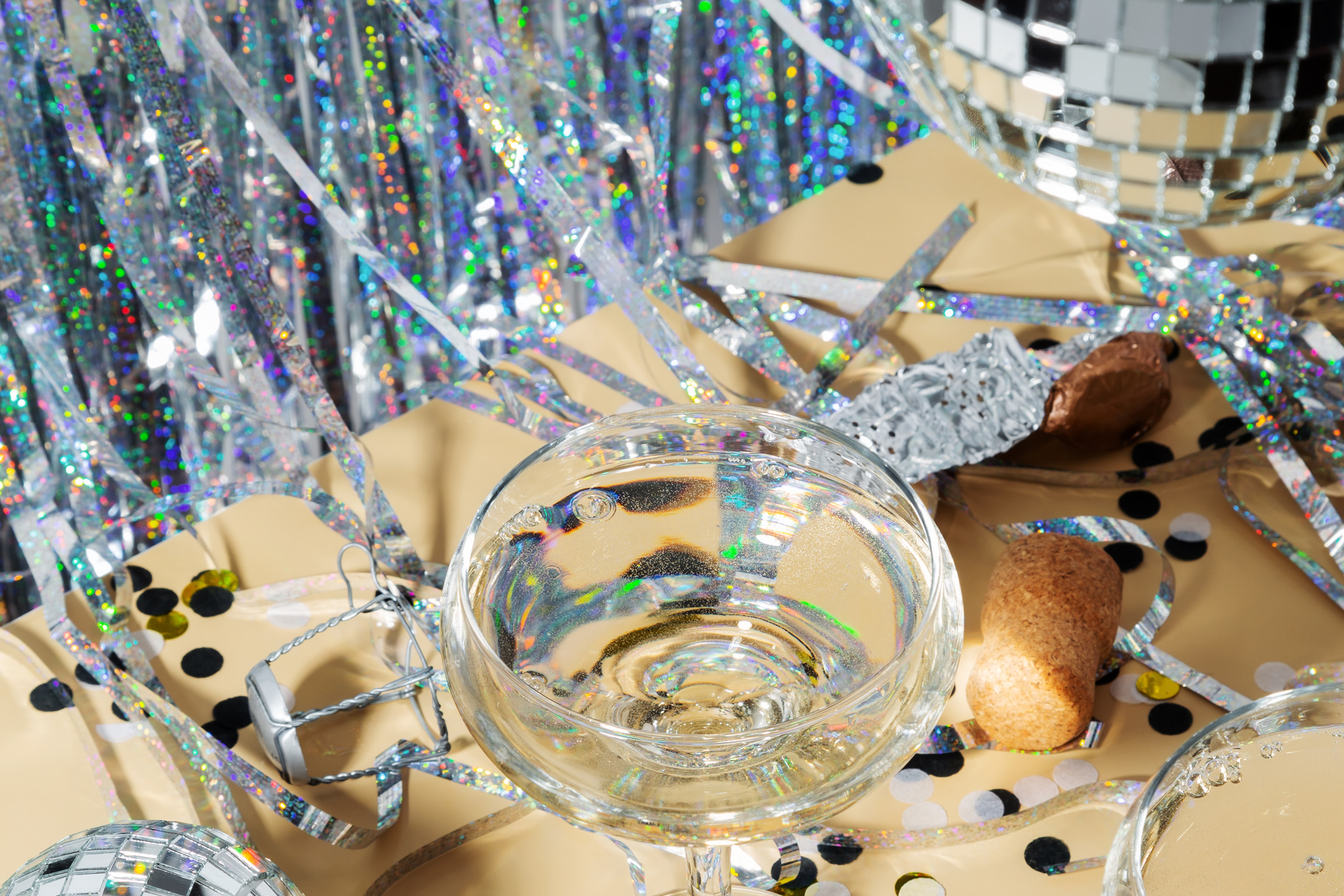 Champagneglas med bubblor, konfetti, glitter och discokulor för fest.