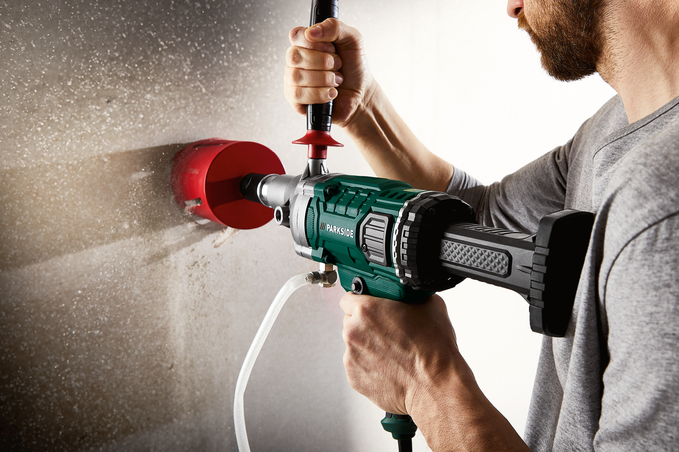 Man borrar i en vägg med en Parkside borrmaskin och en röd hålsåg.