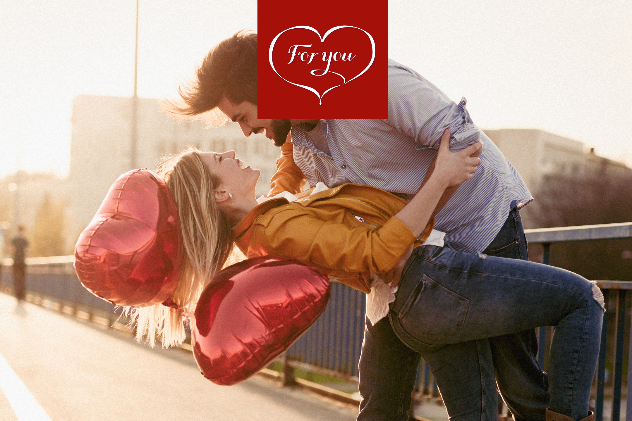 Ett par som kramar varandra med röda hjärtformade ballonger och texten 'For you'.