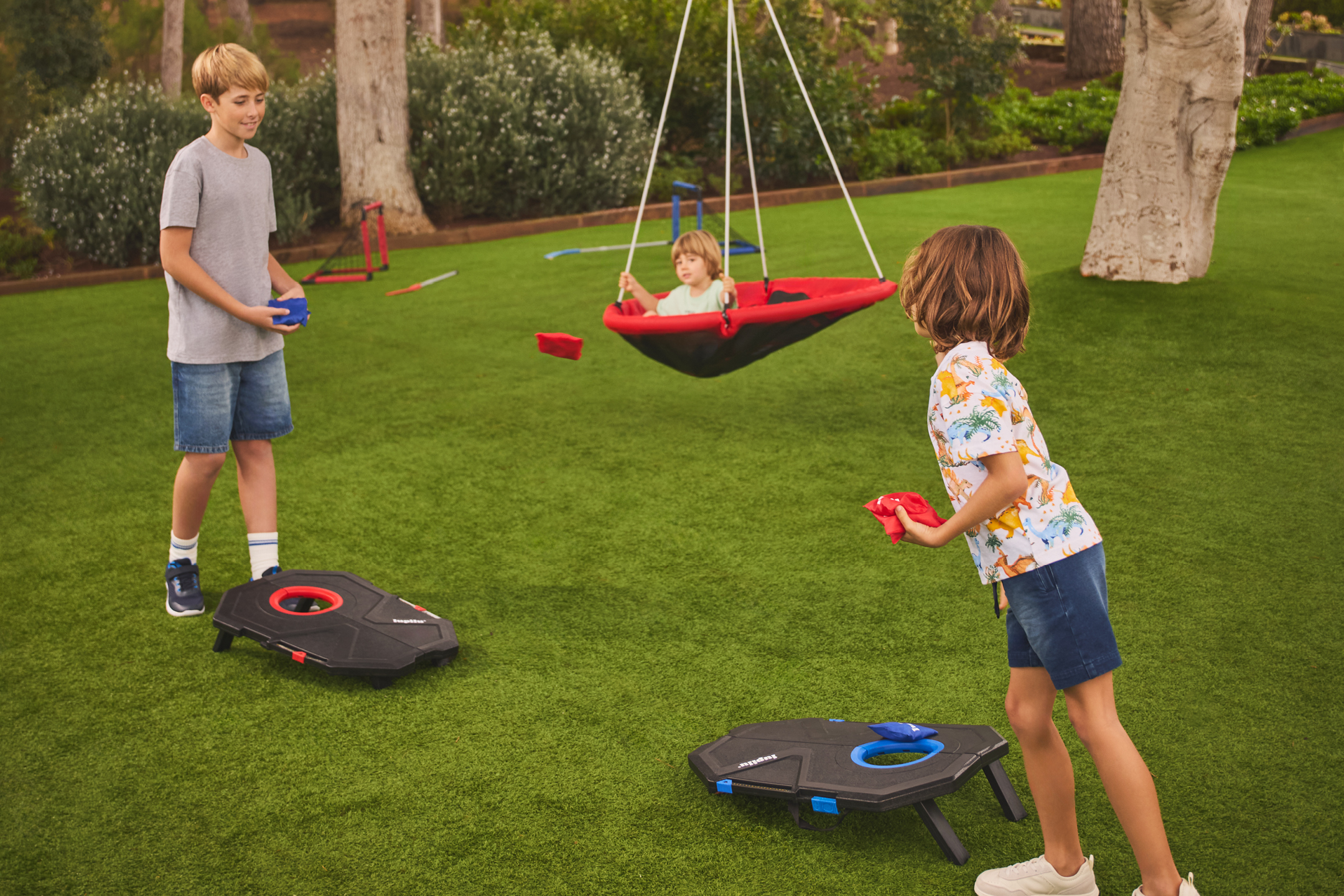 Barn spelar majskastning i trädgården, ett barn sitter i en gunga.