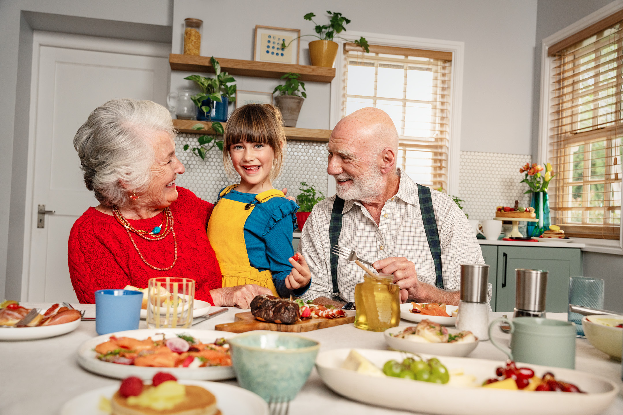 Familj som äter en måltid med kött, fisk, pannkakor och frukt.