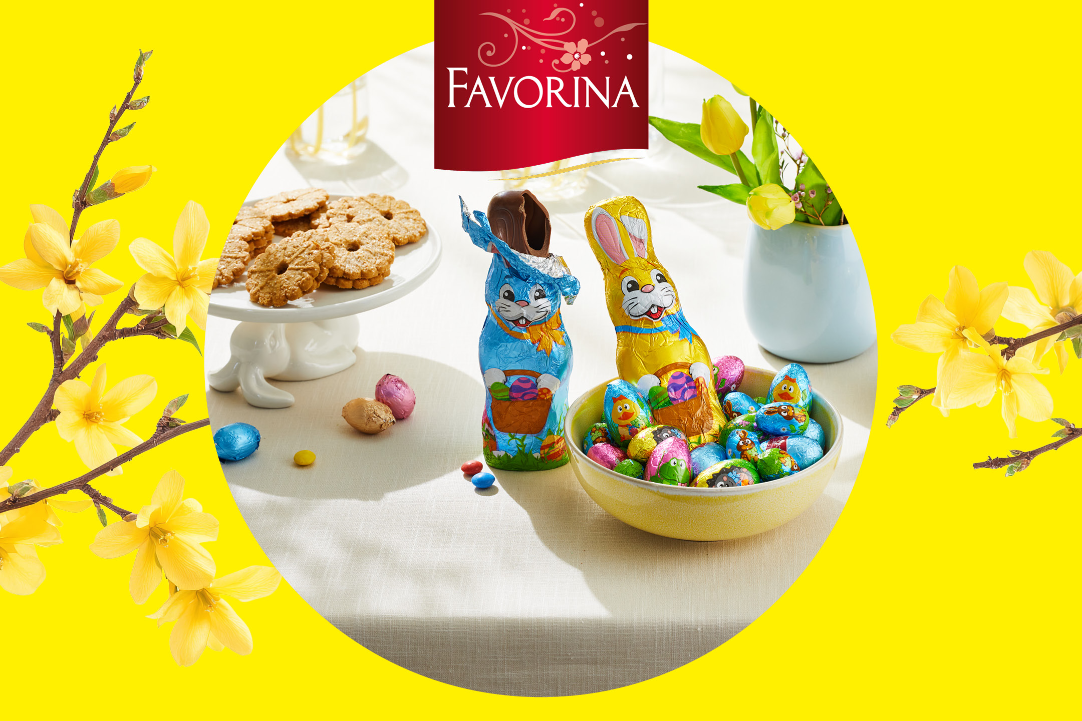 Påskgodis med chokladharar, chokladägg och kakor på ett bord med gula blommor.