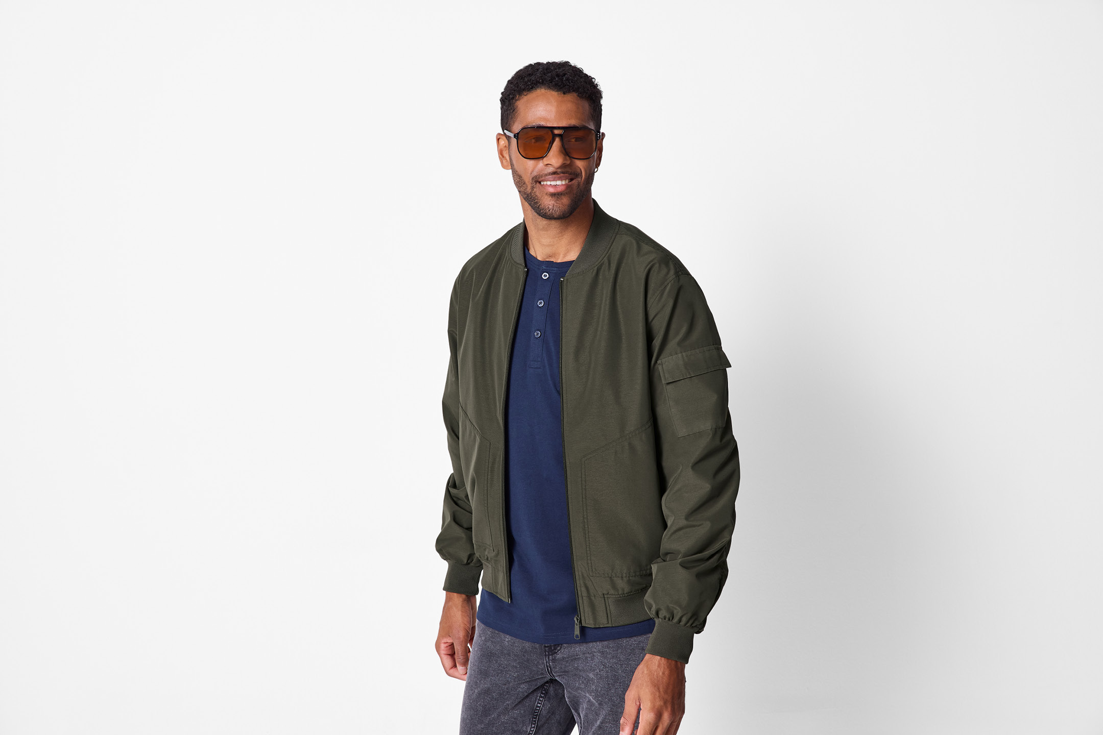 Man i mörkgrön bomberjacka, mörkblå pikétröja och solglasögon.