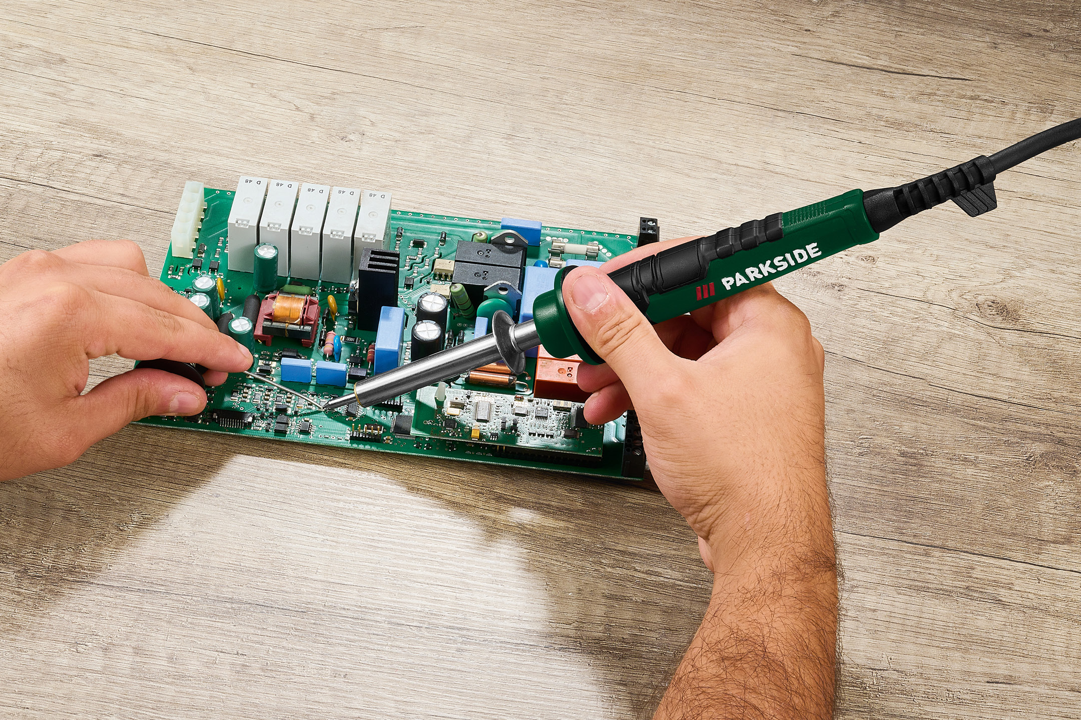 En person löder på ett kretskort med en lödkolv.