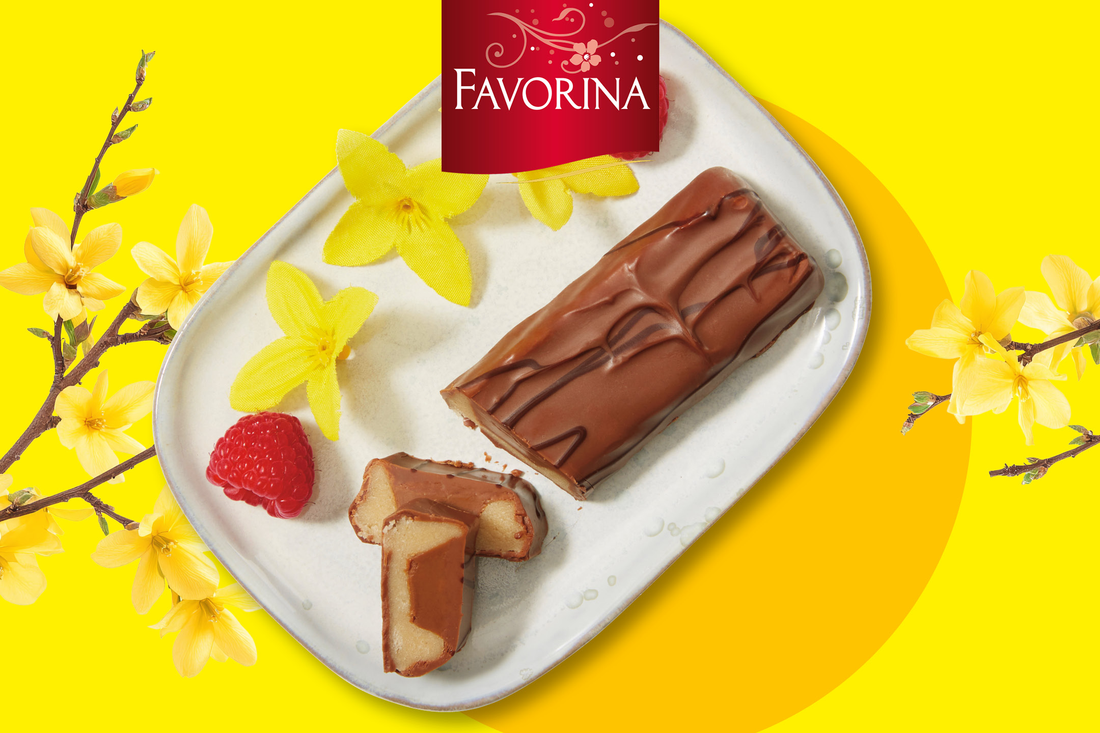 Chokladöverdragen marsipanlimpa med hallon och gula blommor på en vit tallrik.