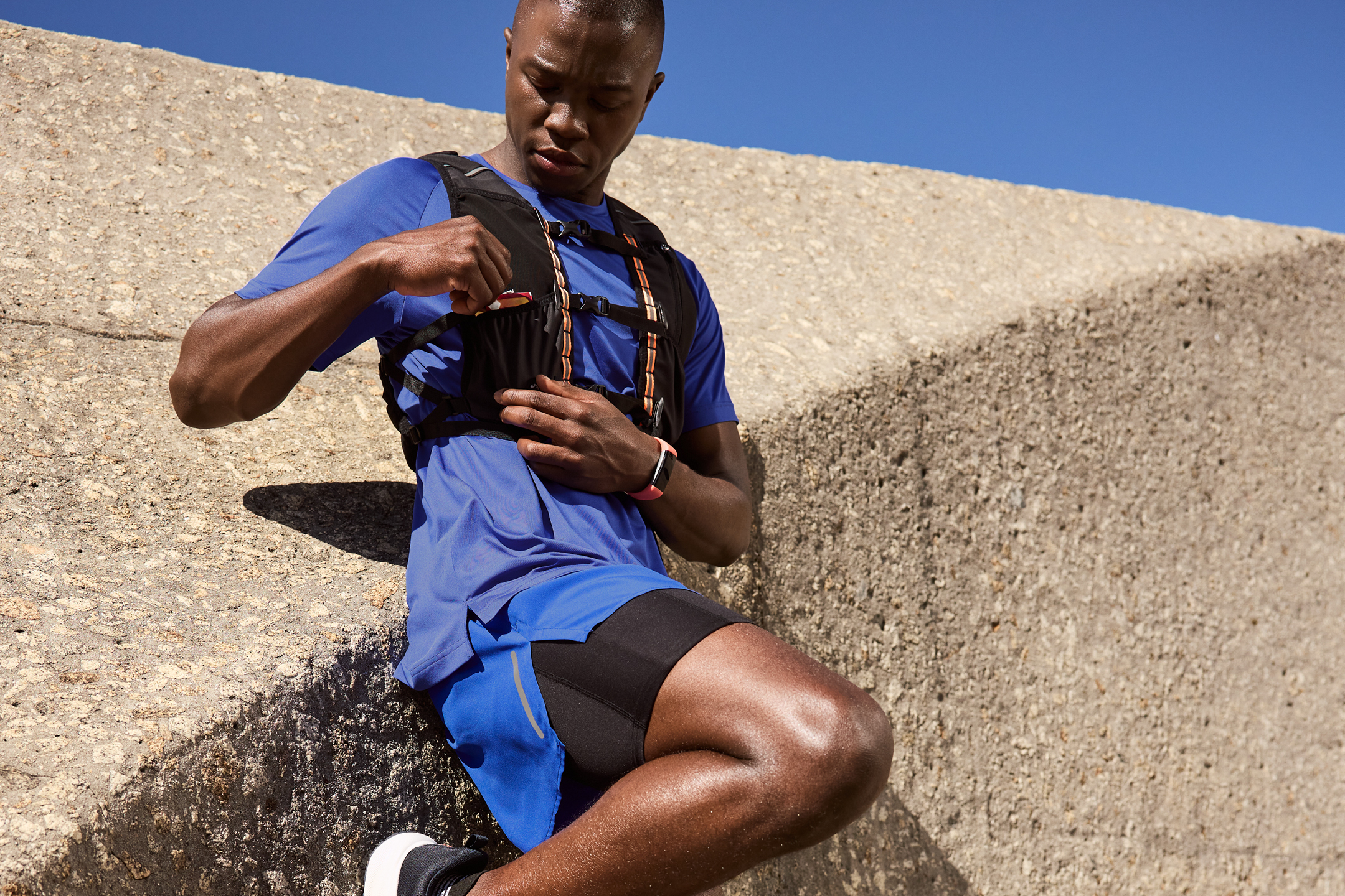 Man i blå träningskläder och löparväst tar en energibar under ett träningspass.