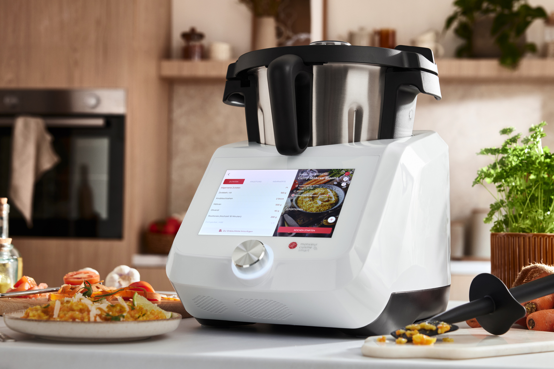 Matberedare med pekskärm som visar ett recept på curry-morotsrisotto i ett kök.