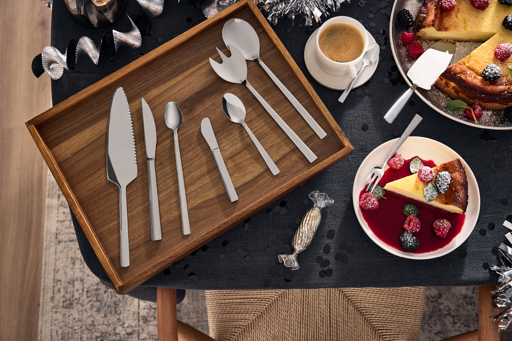 Serveringsbestick och tårtbitar med bär på ett dukat bord.