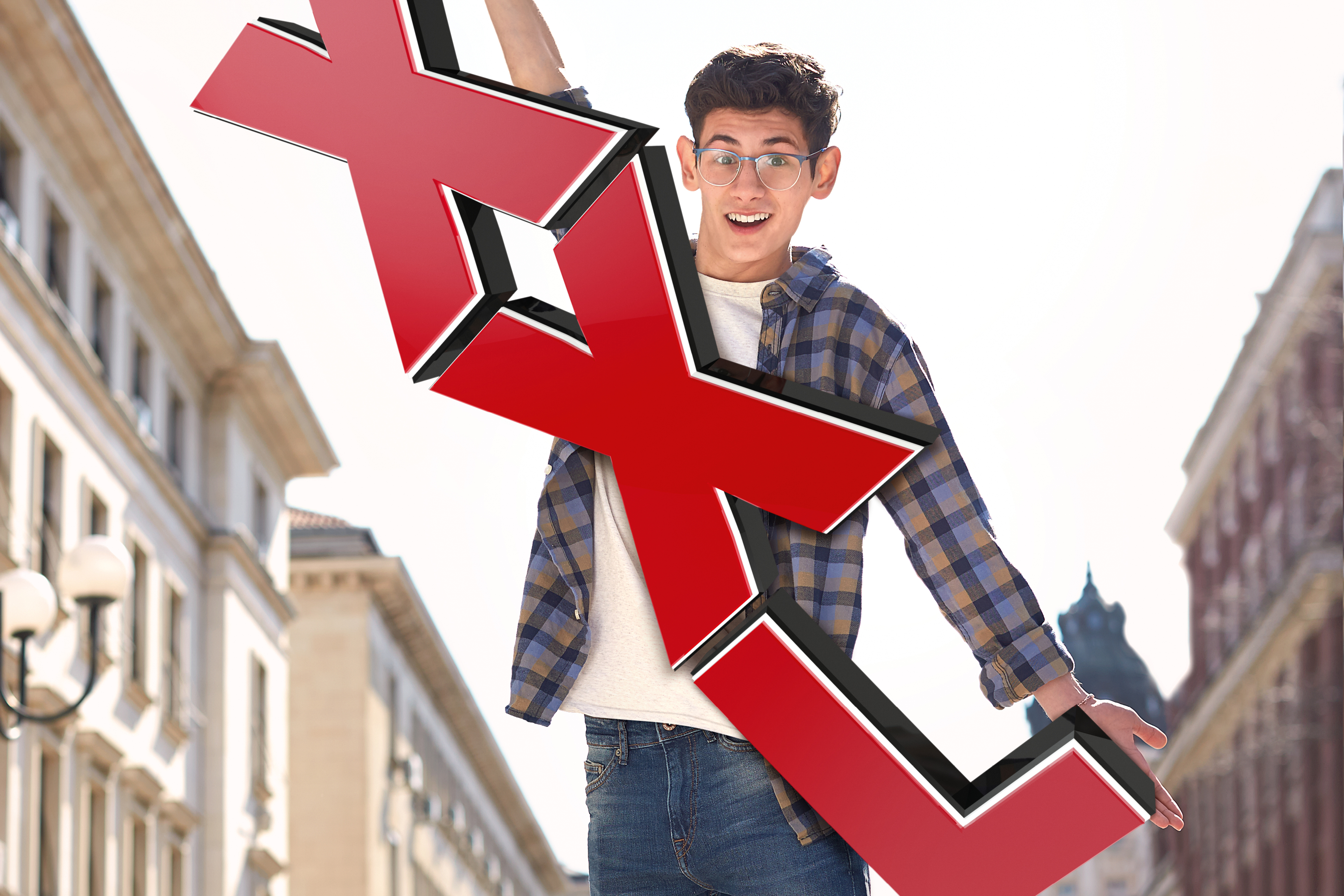 Ung man håller ett stort rött X i en stadsmiljö.