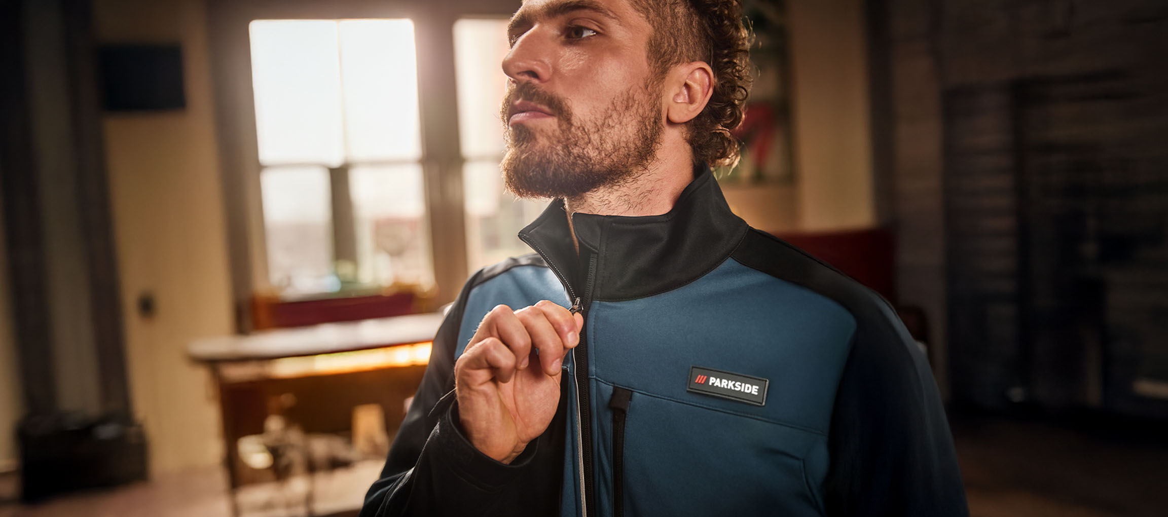Man i en blå och svart Parkside arbetsjacka som drar upp dragkedjan