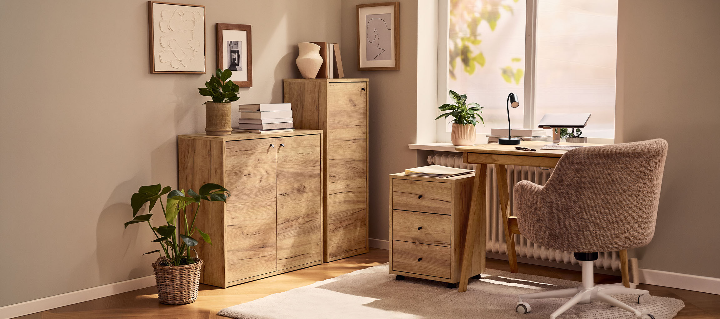 Hemmakontor med träskåp, skrivbord och stol, dekorerat med växter och tavlor.