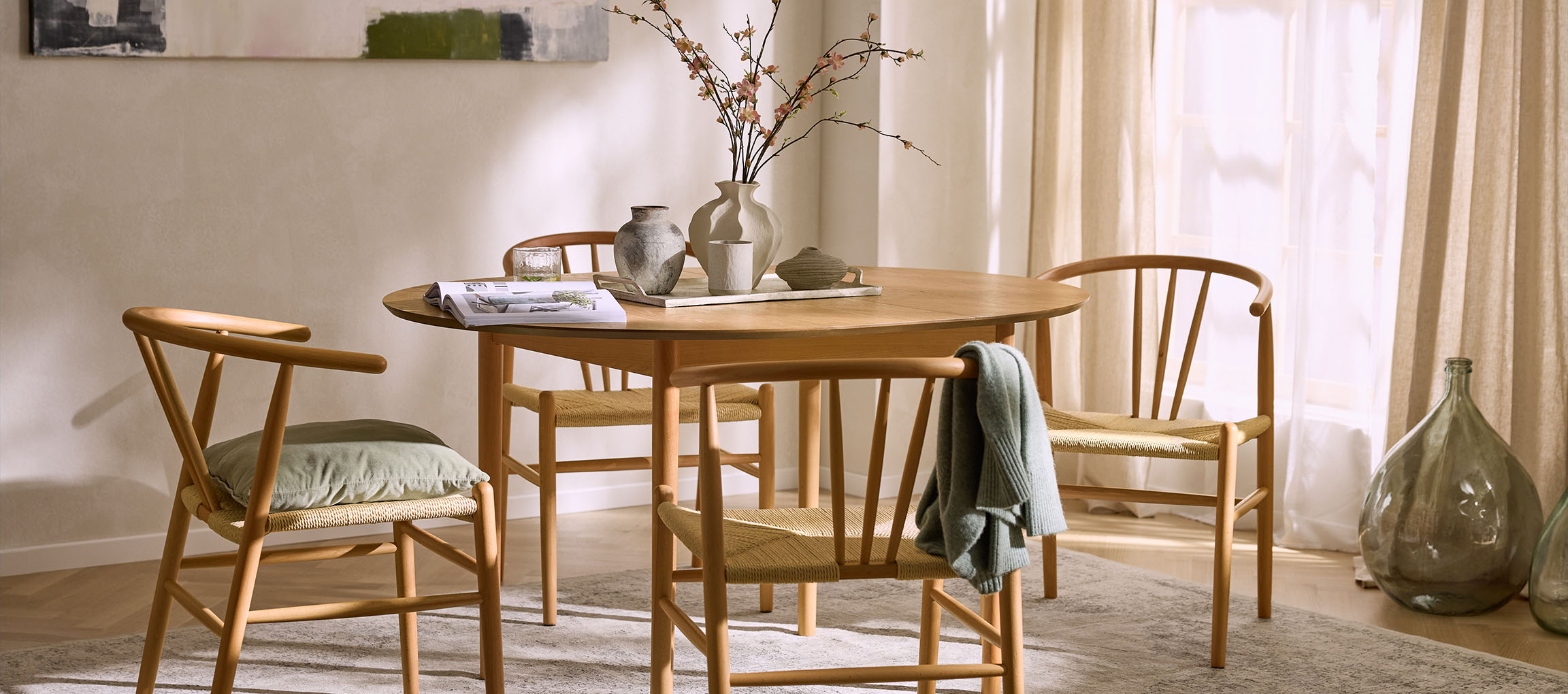 Matsal med runt träbord, trästolar med repsitsar och dekorativa vaser.