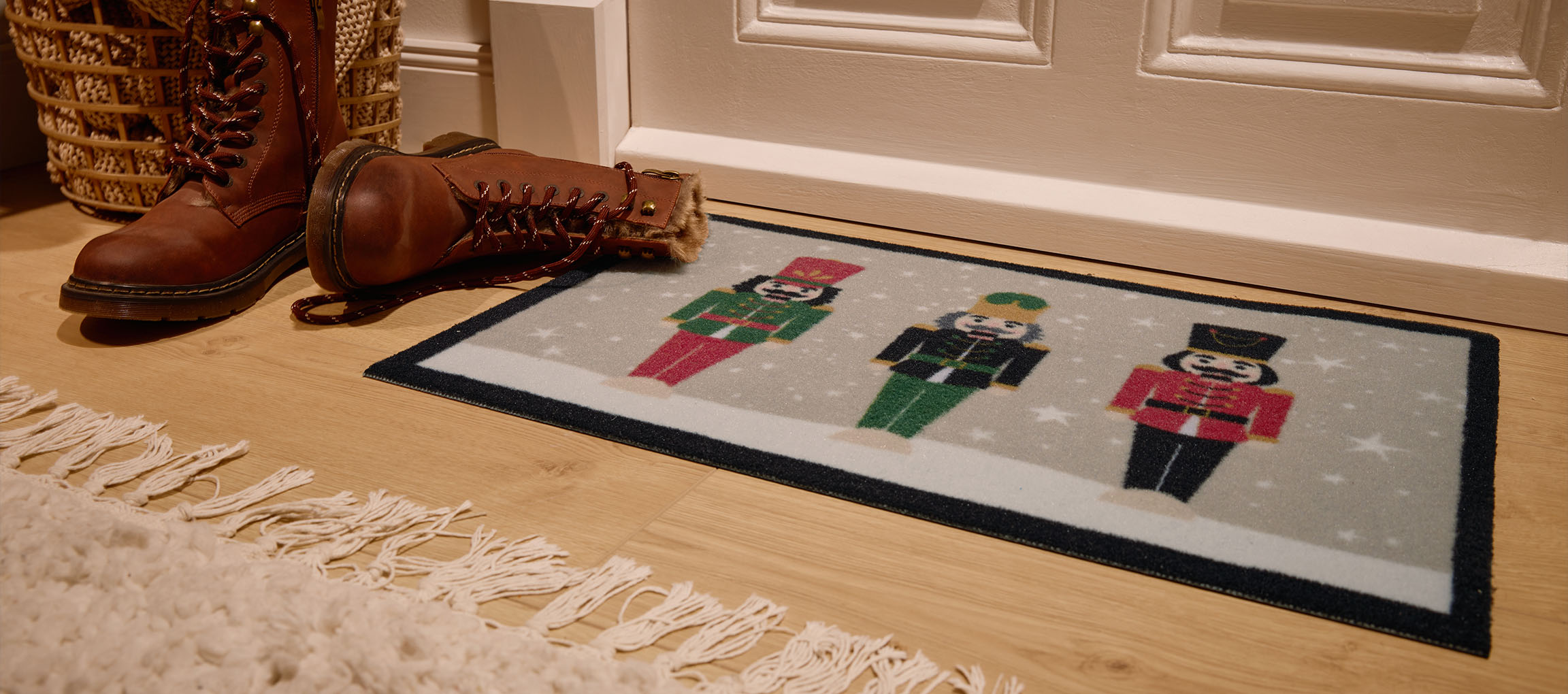 Julmatta med nötknäppare, bruna stövlar och flätad korg vid entrén.