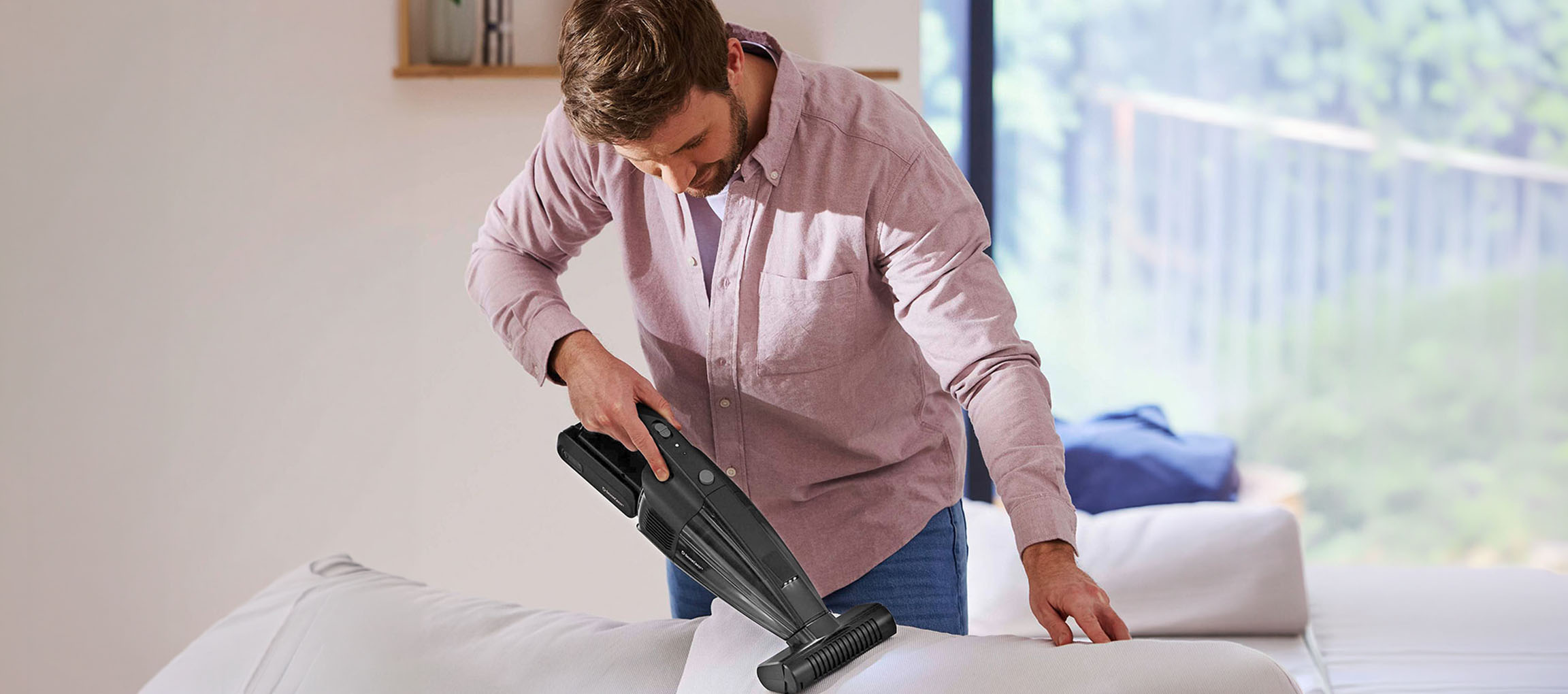 Man rengör en soffa med en handdammsugare.