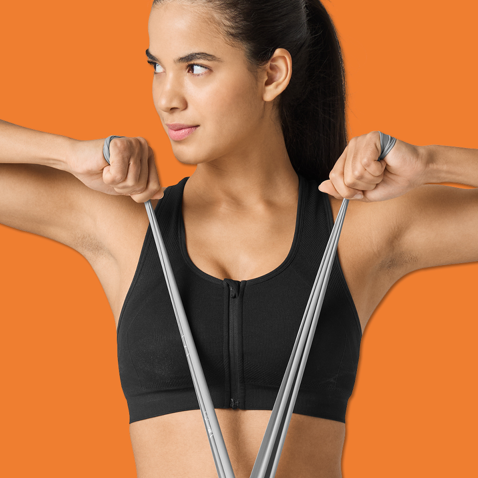 Kvinna i svart sport-bh tränar med ett grått träningsband.