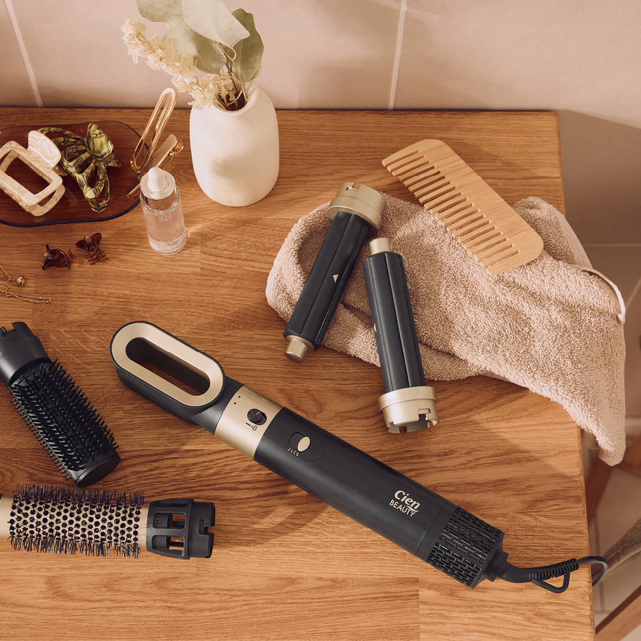 Cien Beauty hårstylingverktyg med utbytbara borstar, hårklämmor och kam på träbänk.