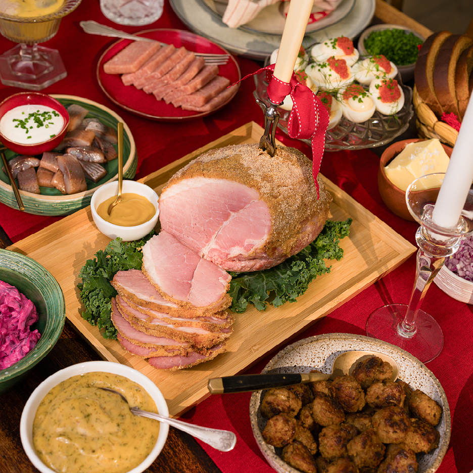 En julskinka med senap, köttbullar, sill och andra rätter på ett julbord.