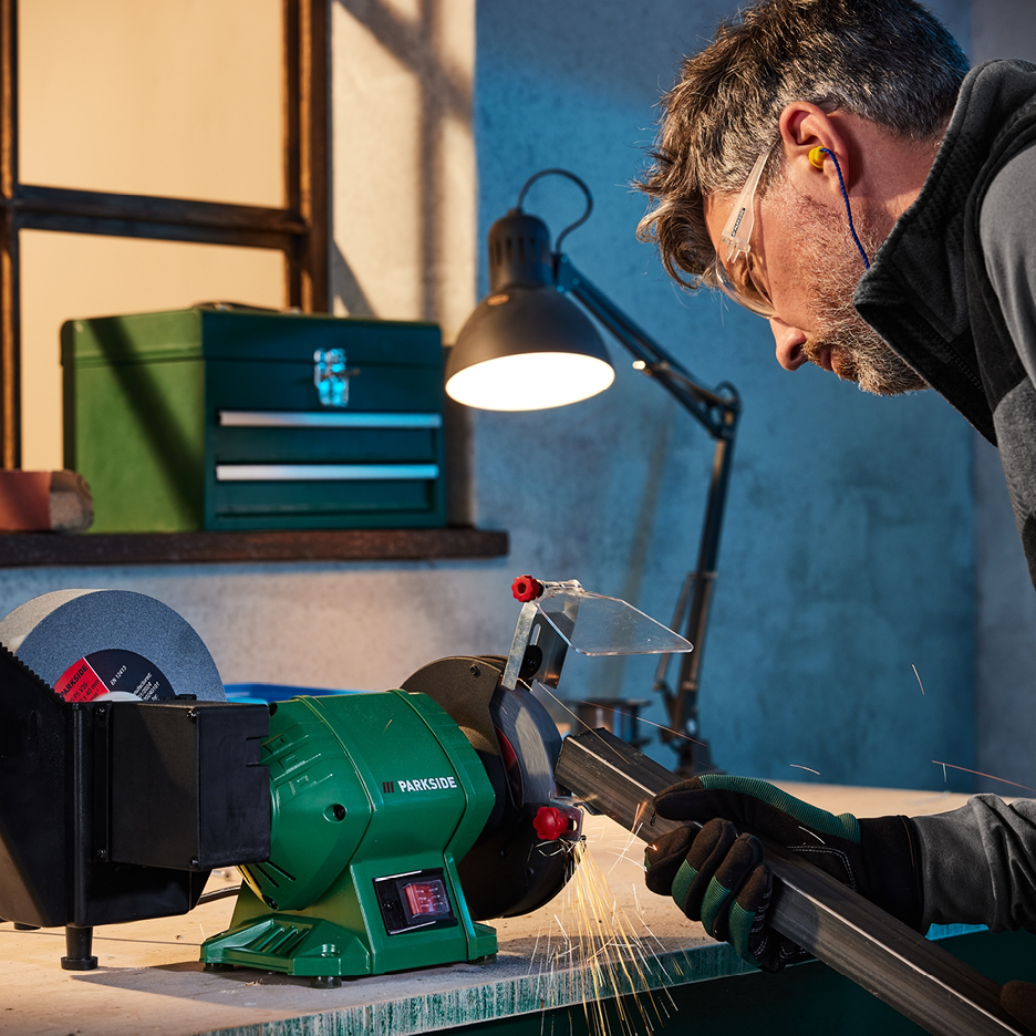 Man slipar metall med en Parkside bänkslipmaskin, gnistor flyger.