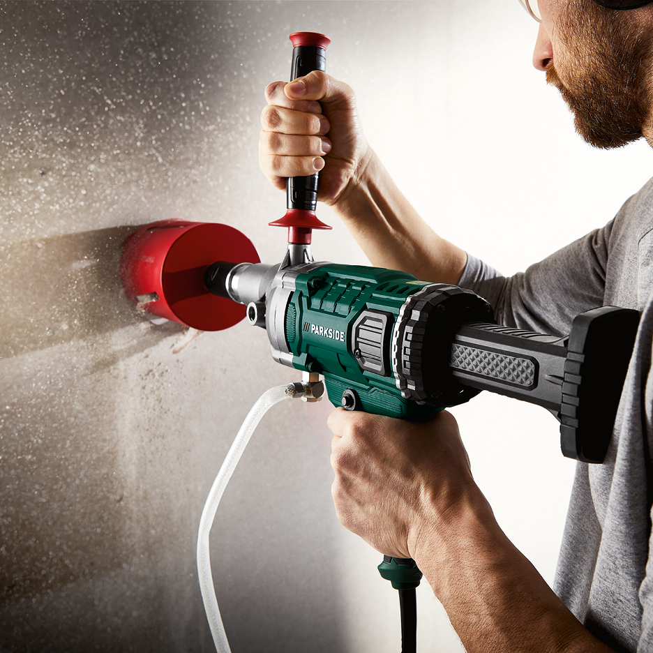 Man borrar i vägg med en Parkside kärnborrmaskin och röd kärnborr.