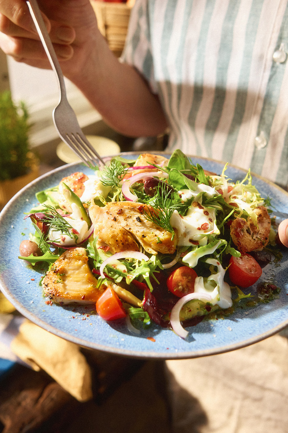En fräsch kycklingsallad med grönsaker och dressing serverad på en tallrik.