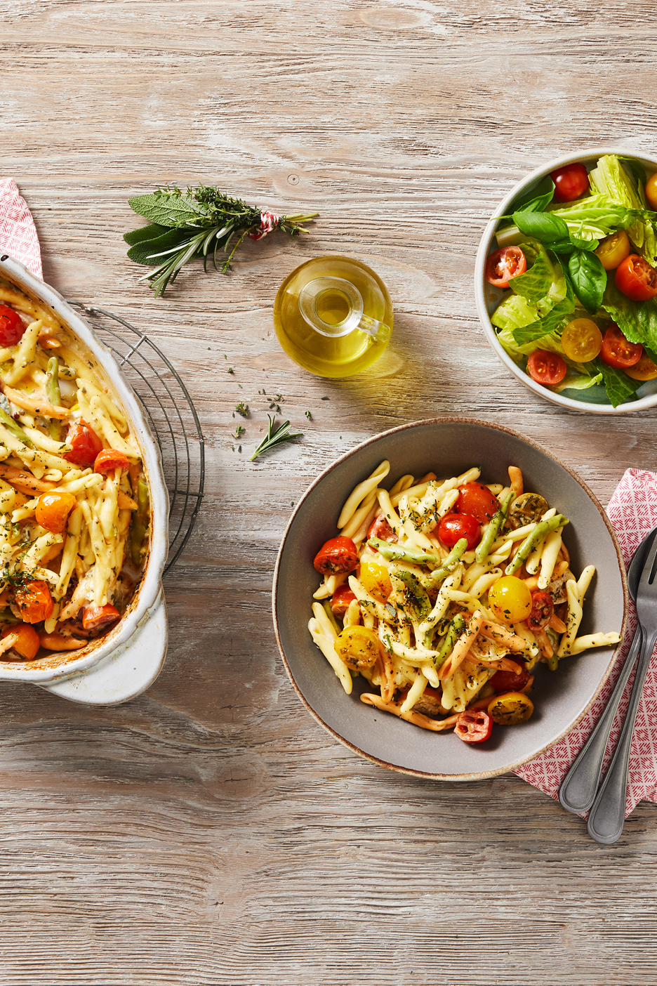 Pastagratäng med tomater och grönsaker, serverad med sallad och olivolja.