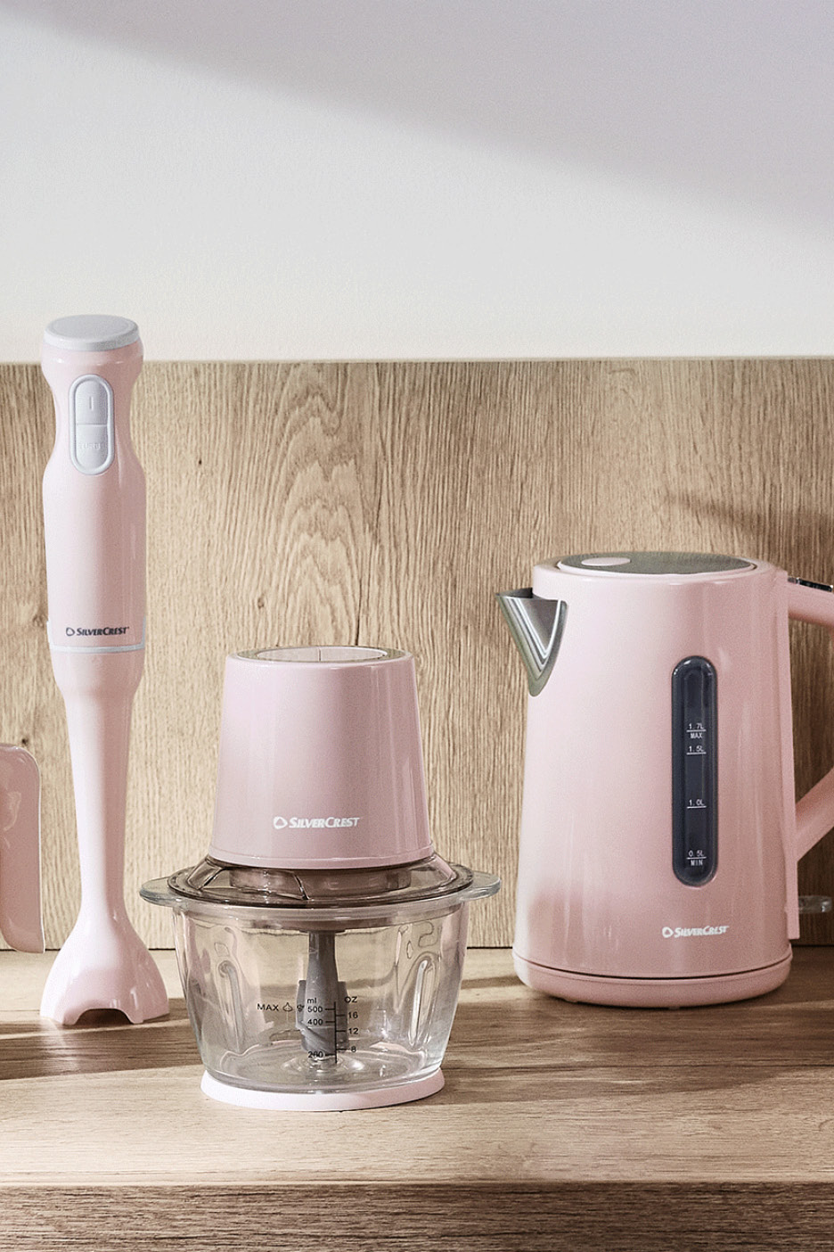 Rosa stavmixer, minihackare och vattenkokare på en träbänk.