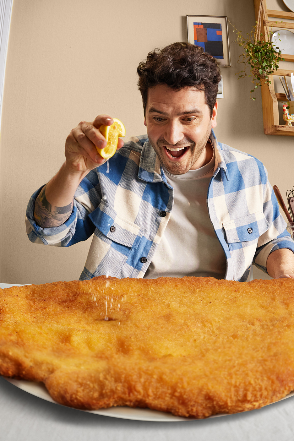 Man pressar citron över en stor, krispig schnitzel.