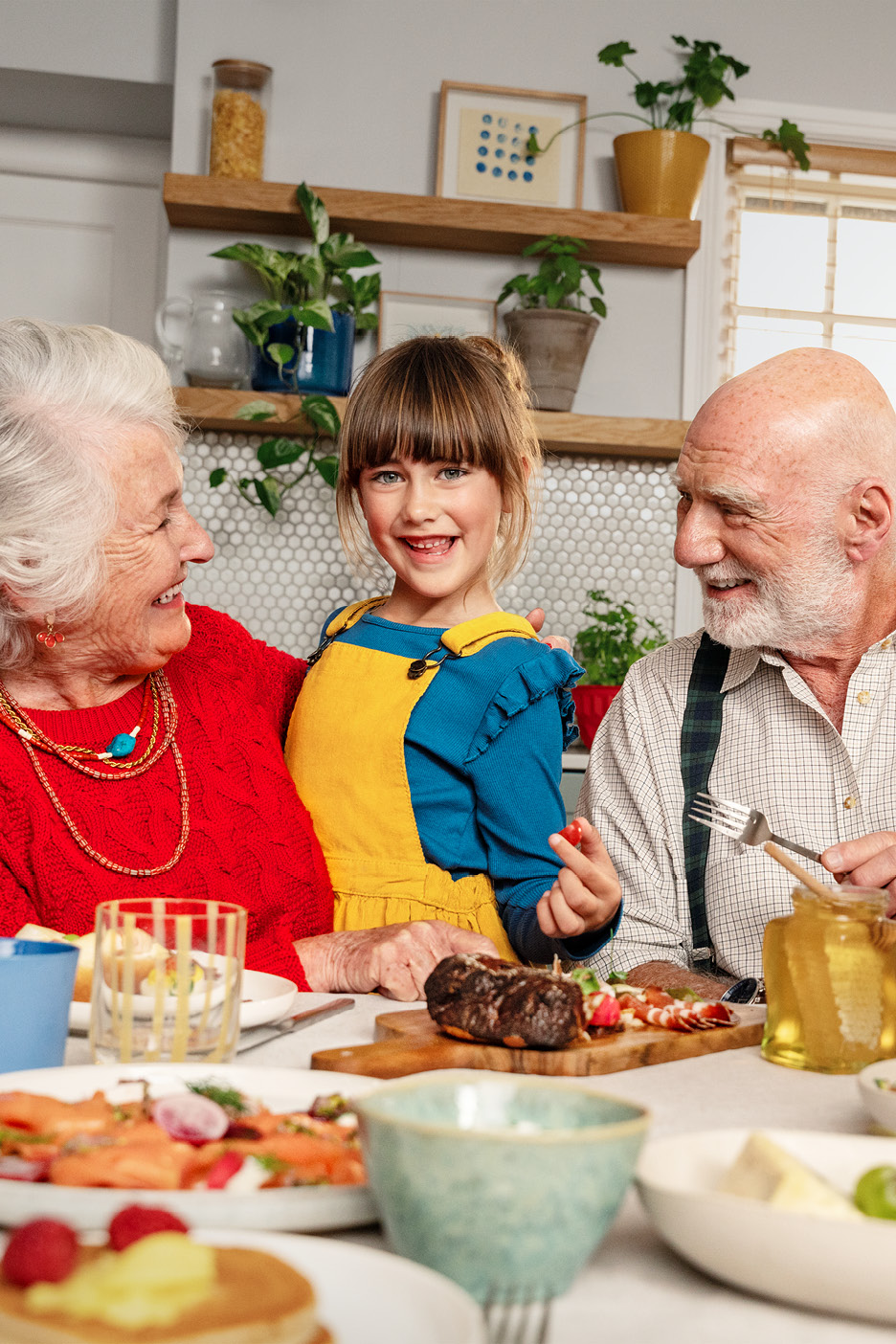 Familj vid frukostbordet med pannkakor, lax och kött.