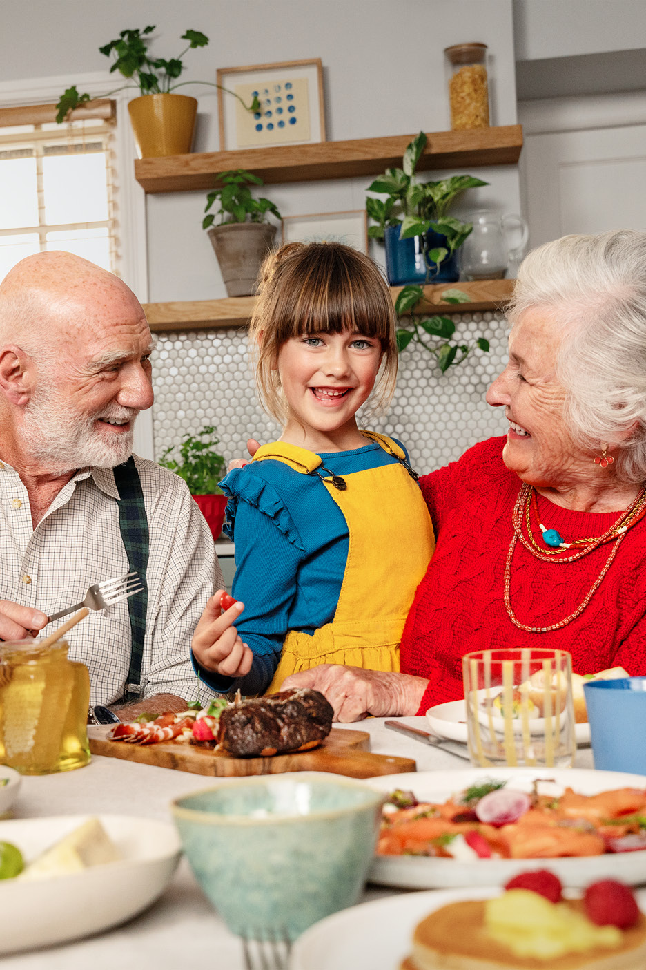 Familj vid middagsbordet med kött, lax och pannkakor.