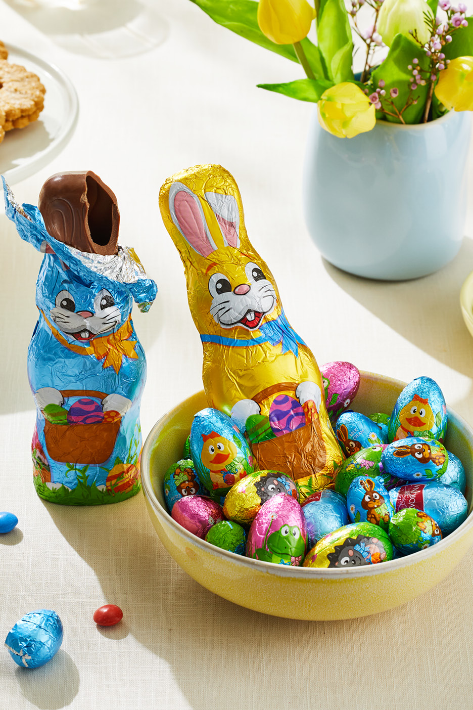 Påskchoklad: en guldfärgad chokladhare i en skål med folieinslagna ägg, bredvid en blå chokladhare.