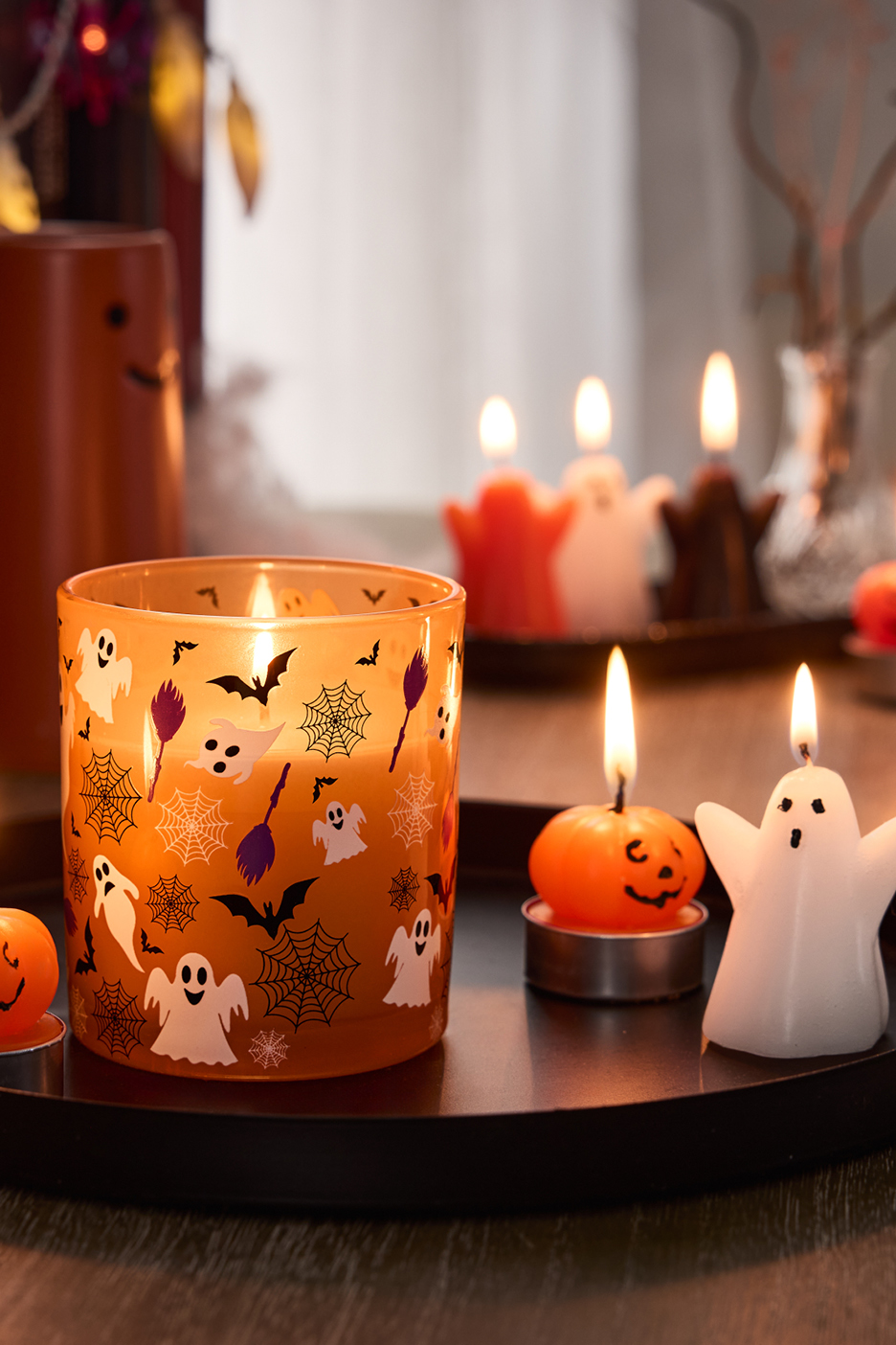 Halloween-ljus i form av spöken och pumpor, samt ett ljus i en glasburk med spökmotiv.