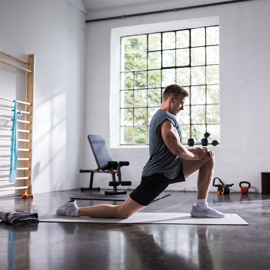 Man stretchar på en yogamatta i ett gym.