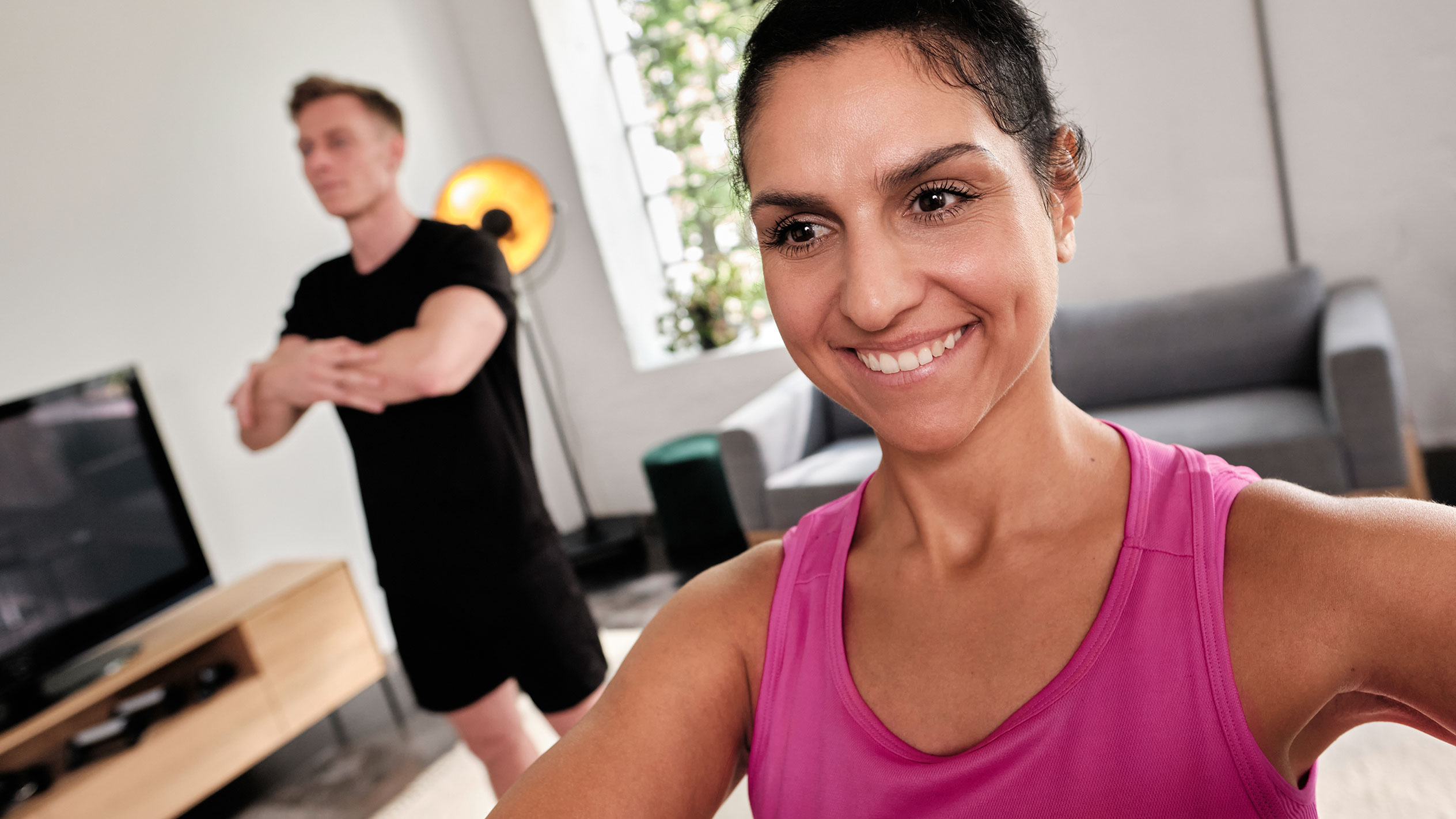 Leende kvinna som tränar hemma med sin partner.