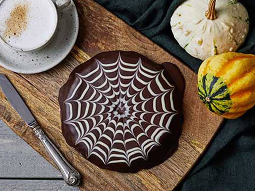 Chokladkaka med spindelnätsdesign, pumpor och kaffe.