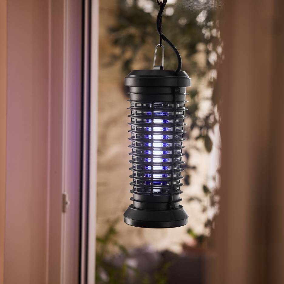 Elektrisk insektsfälla med blått ljus hängande vid ett fönster.