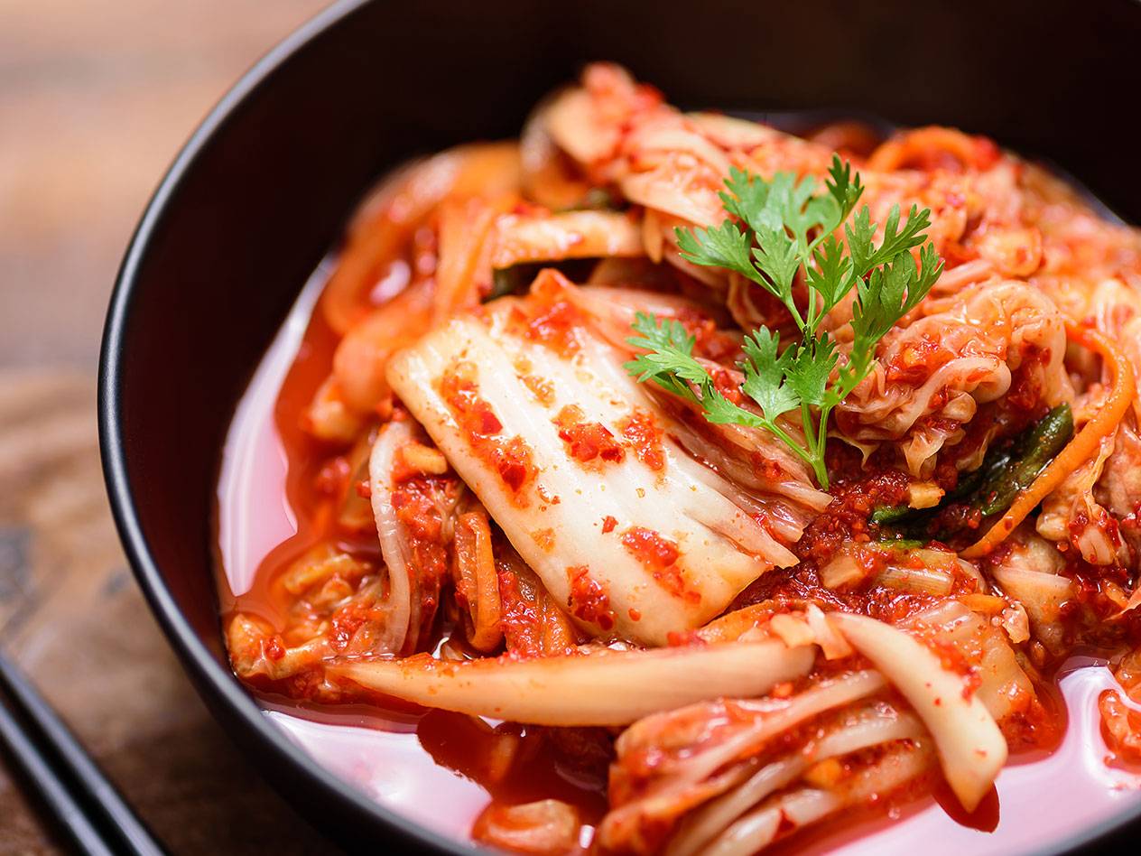 Kimchi i en svart skål, toppad med färsk koriander.